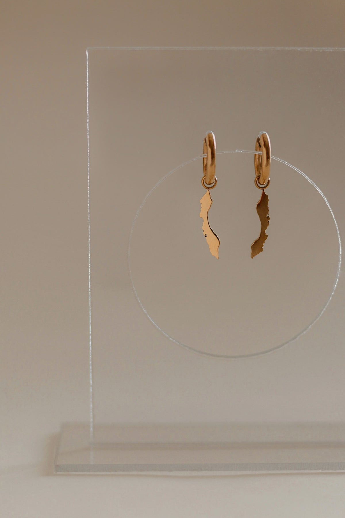 Gold Curaçao island silhouette earrings on small huggie hoops