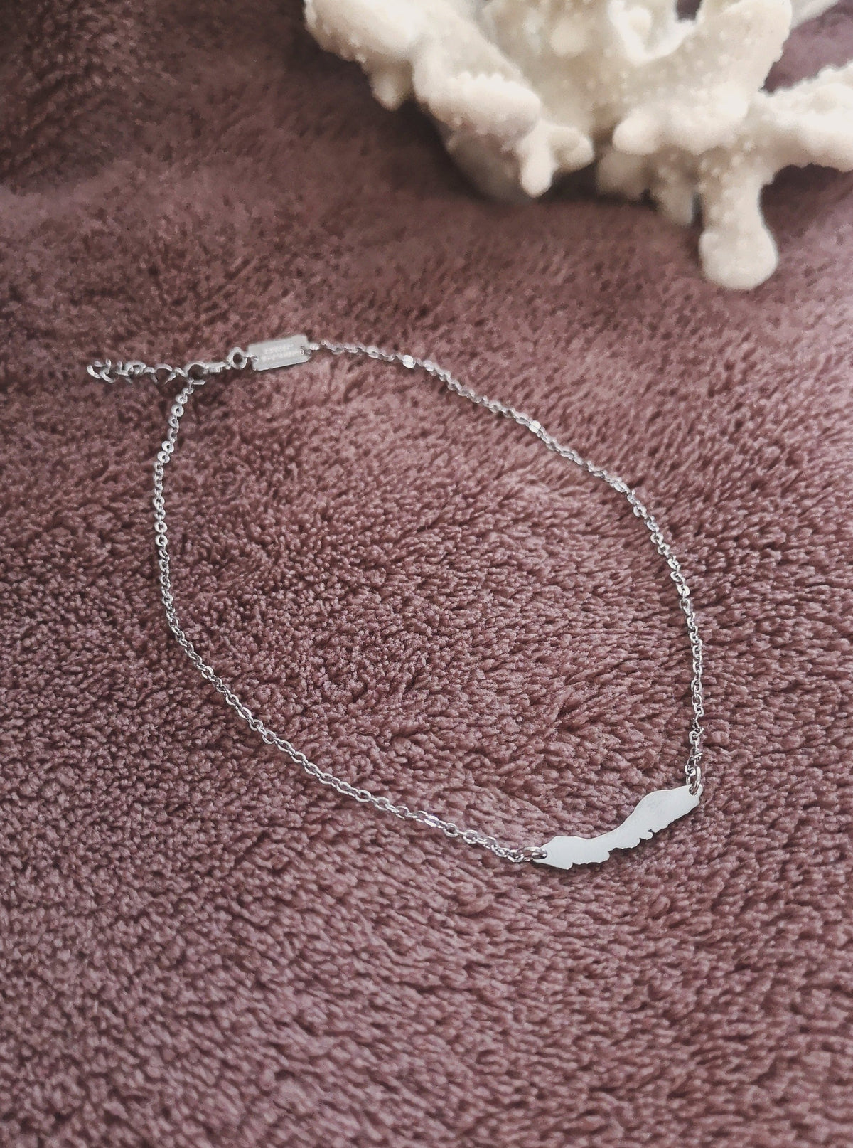Close-up of silver-tone OG Curaçao anklet with island charm