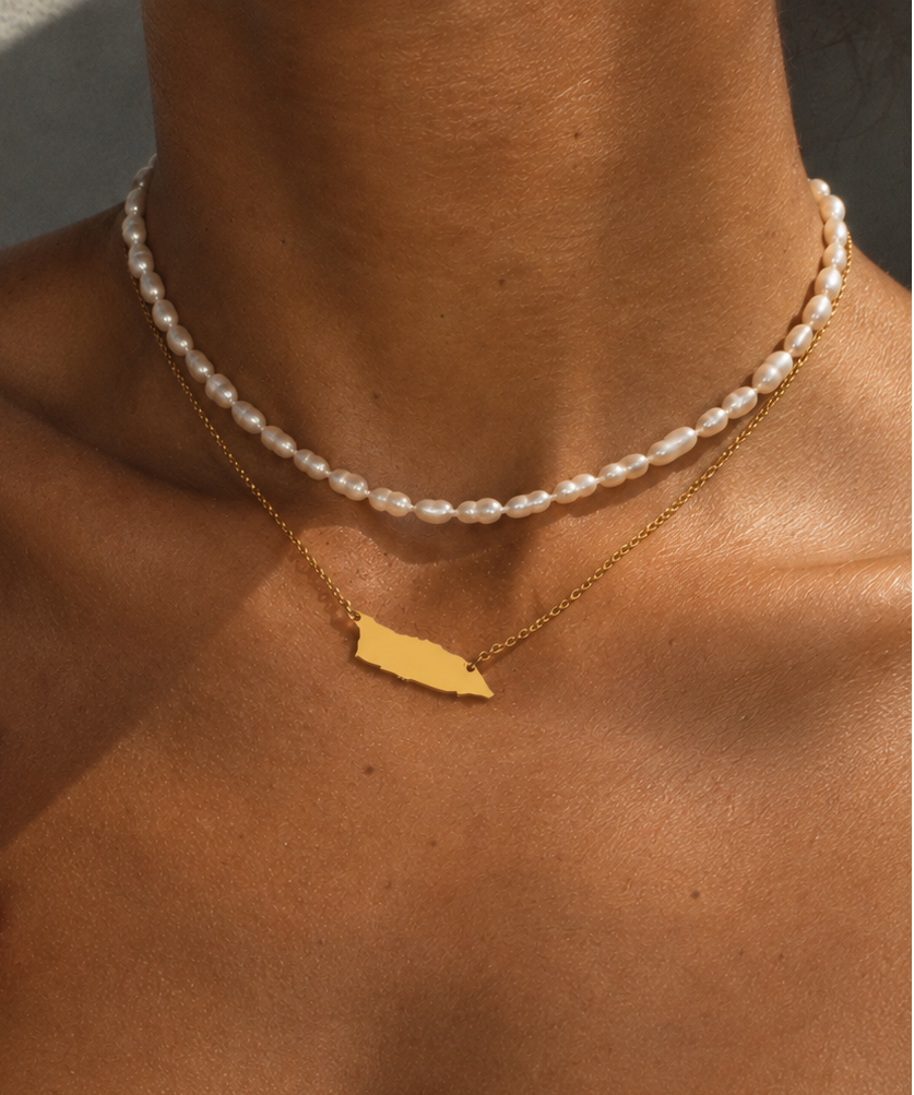 A close-up lifestyle shot of a model wearing the Aruba Necklace combined with a pearl