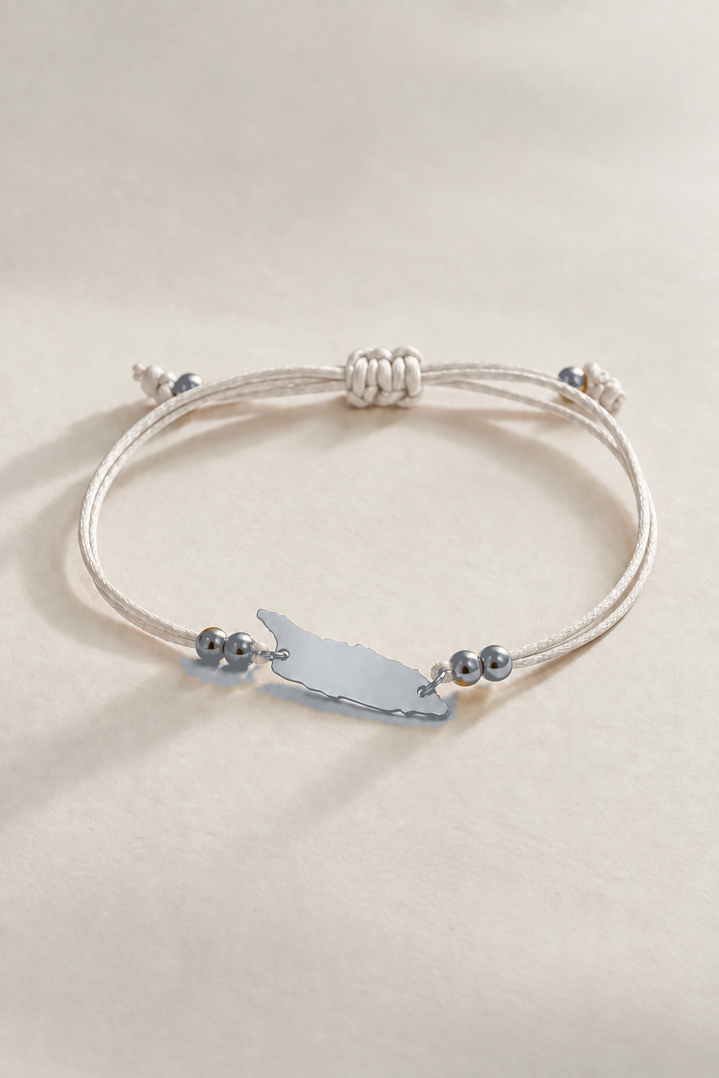Silver-tone Aruba island charm on cream cord bracelet
