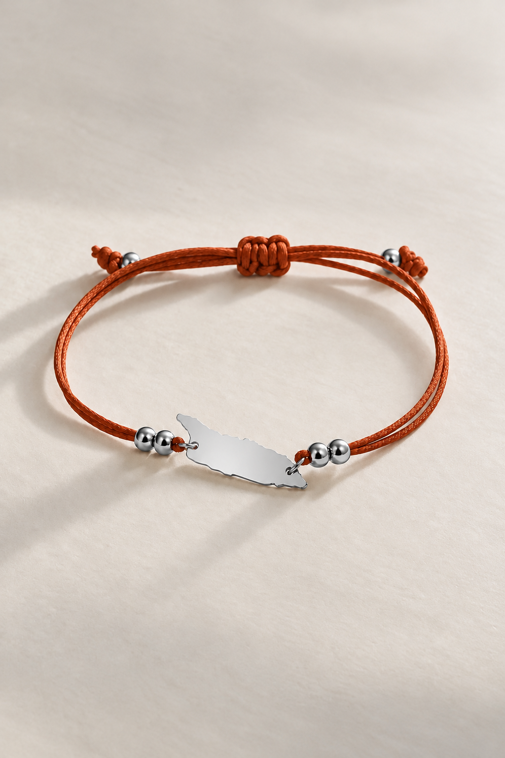 Silver-tone Aruba island charm on copper brown cord bracelet