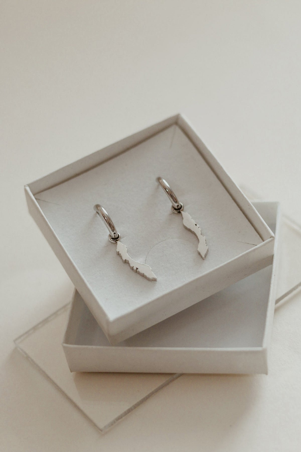 OG Curaçao island charms hanging from silver-tone huggie hoops